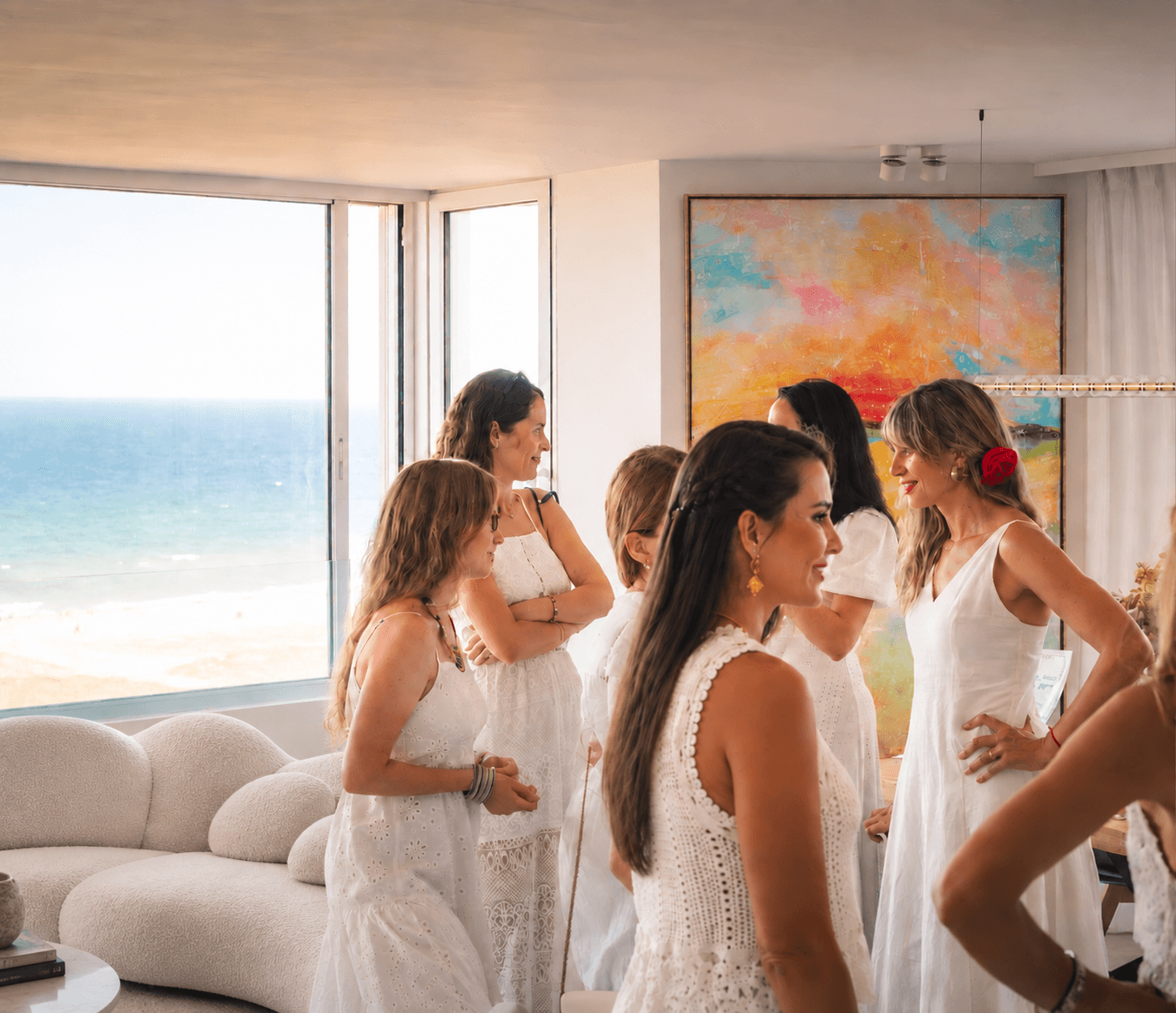 Paula de Motta painting in a coastal interior with guests gathered nearby